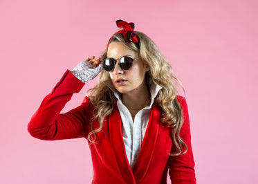 a model in red suit jacket removing sunglasses