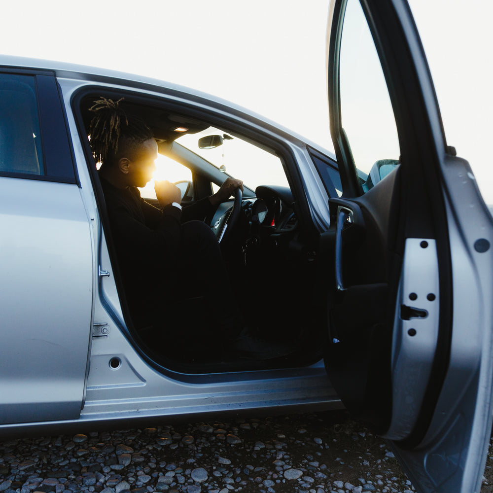 a model in the driving seat silhouetted by sunlight