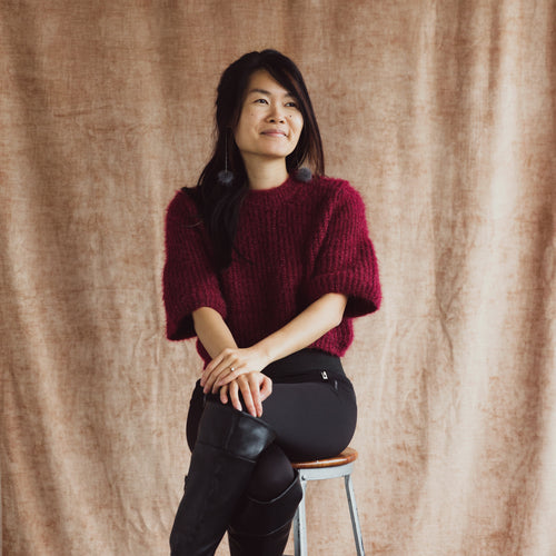 A Model Perched On A Stool Smiles