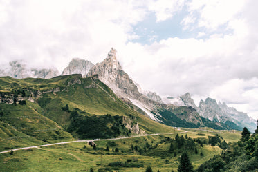 a mountain road through green fields