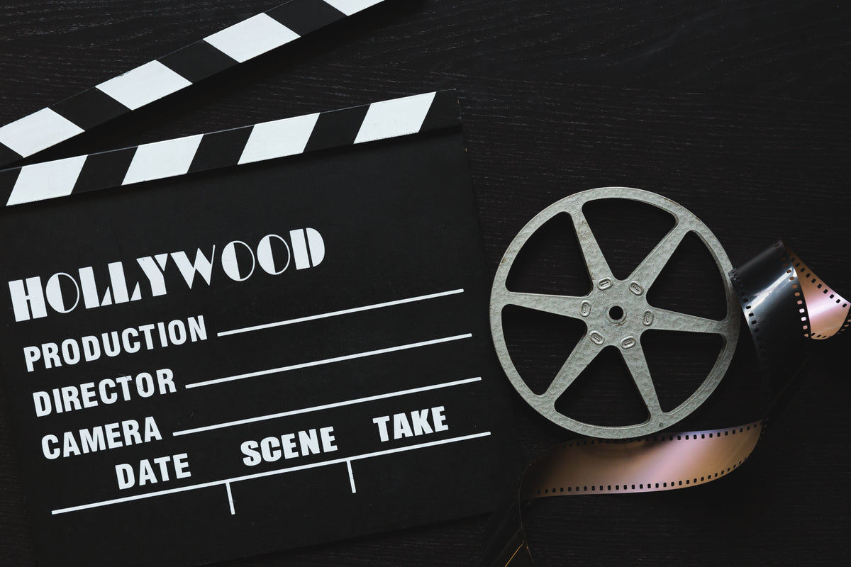 a movie clapper board, film roll and sprocket wheel
