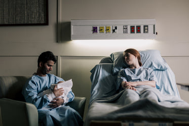 a new father sits in a chair holding his newborn baby