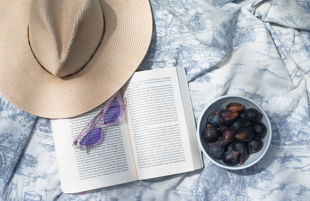 a novel lays open with a bowl of fresh figs next to it