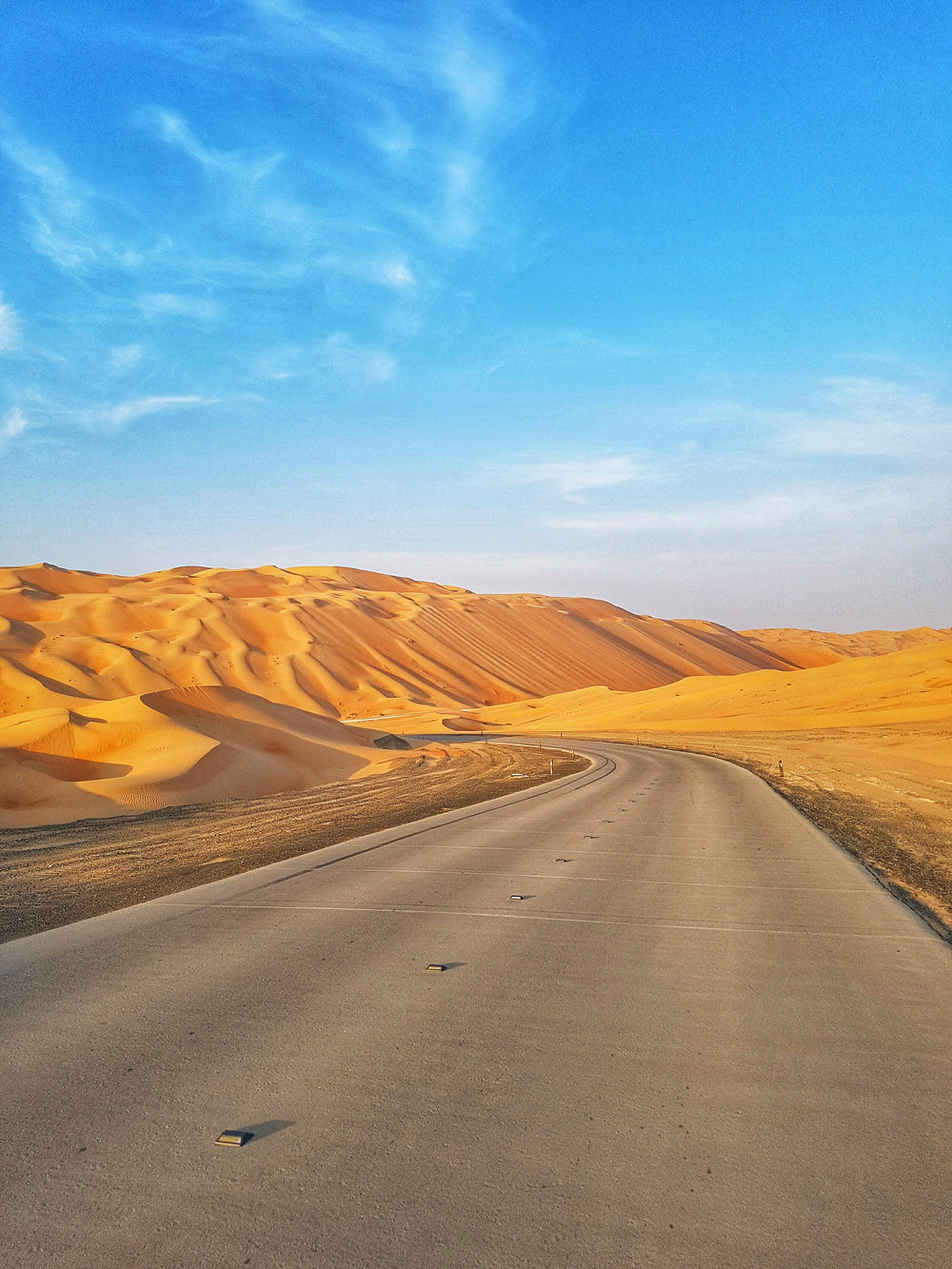 a paved road turns into tall sand dunes