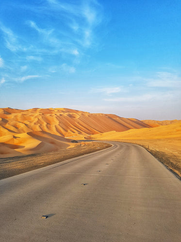 a paved road turns into tall sand dunes