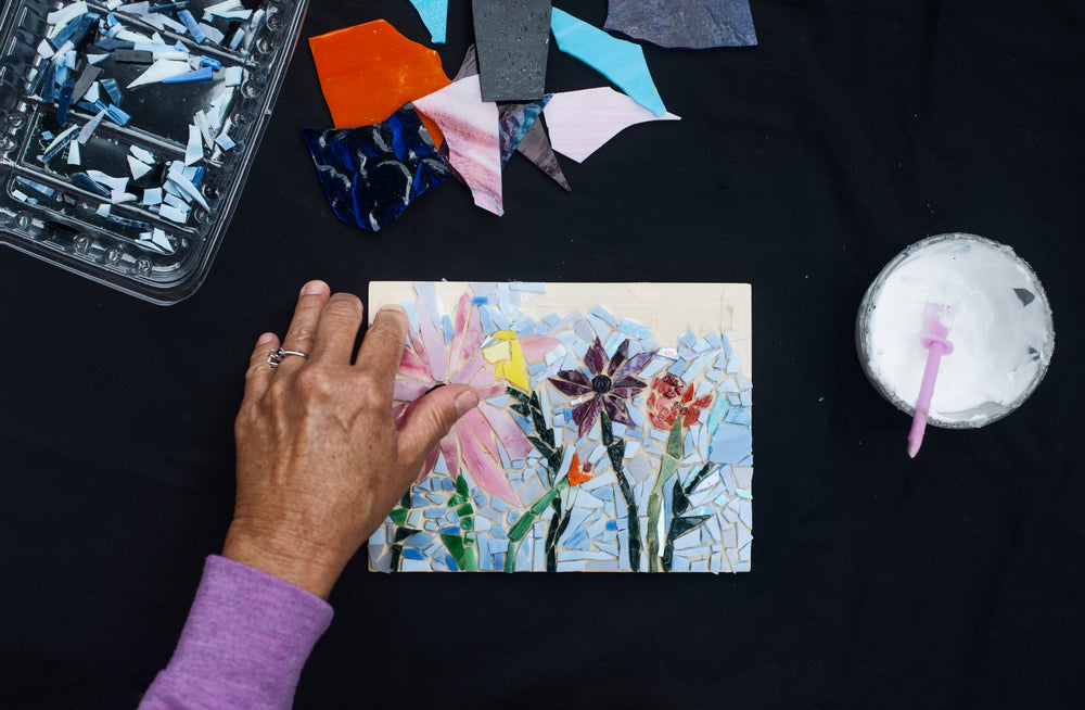 a person adding glass to their mosaic of flowers