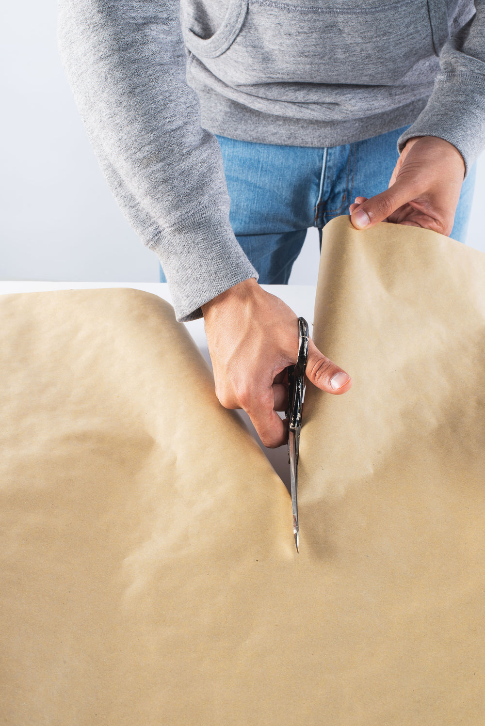 a person carefully cuts through kraft paper