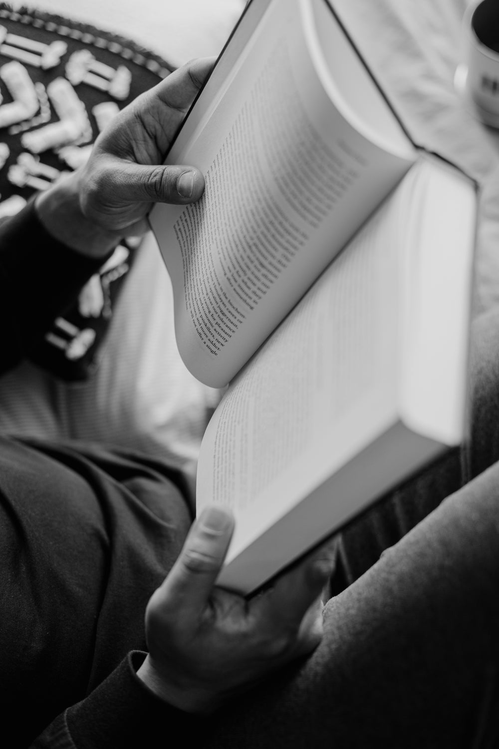 a person holding an open novel in black and white