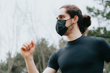 a person in black outdoors with one arm up