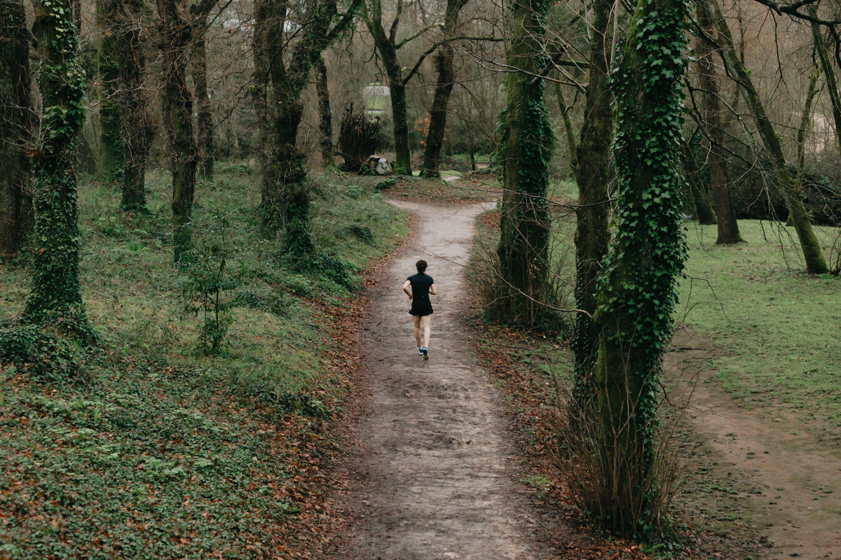 a person in black running on a country trail