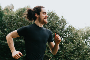 a person in black smiling as they run outdoors