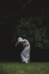 a person in white netting strikes a pose in the woods
