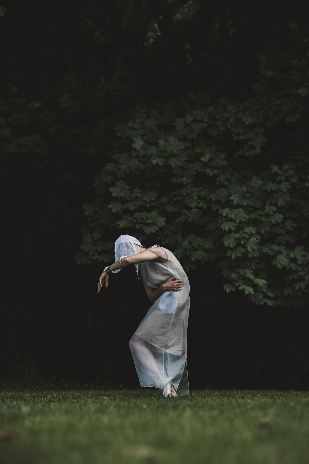 a person in white netting strikes a pose in the woods