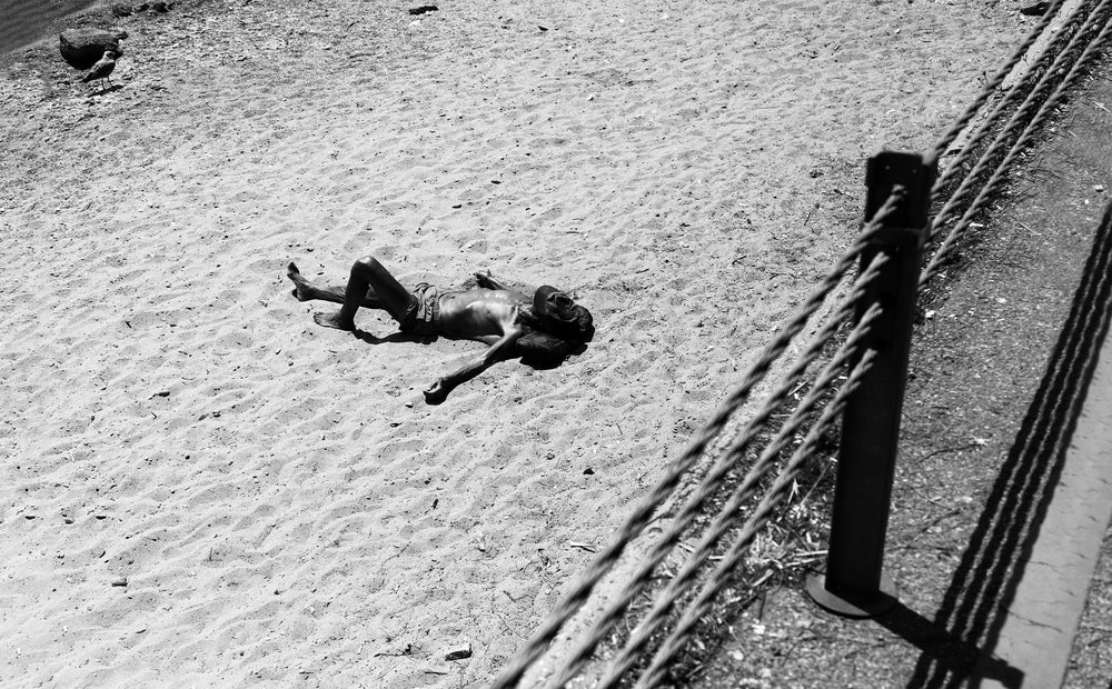 a person laying in the sand with hat over their face