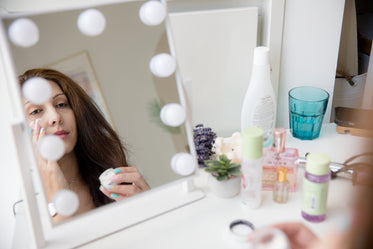 a person looks into a mirror rubbing in face cream
