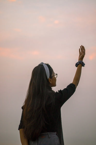 a person with long hair holding arm up to the sky