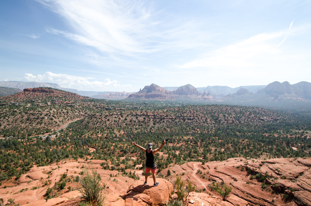 a photographer poses overlooking the plains with arms open