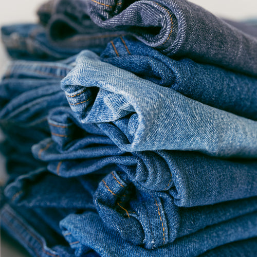 A Pile Of Denim Jeans In Different Shades Of Blue