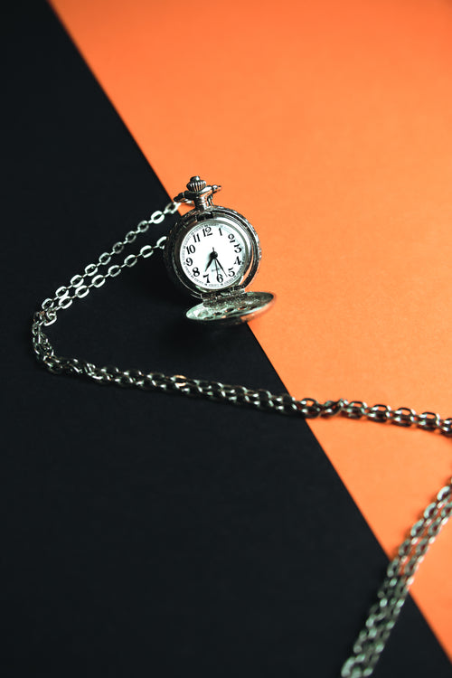 a pocket watch laying on a black and orange background