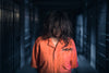 a prisoner standing in orange jumpsuit
