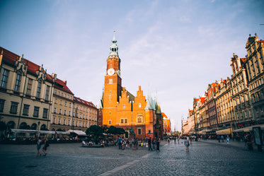 a red brick clock tower and church in a piazza at sunset