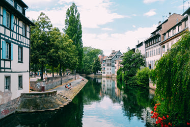 a river winds past historic buildings and trees