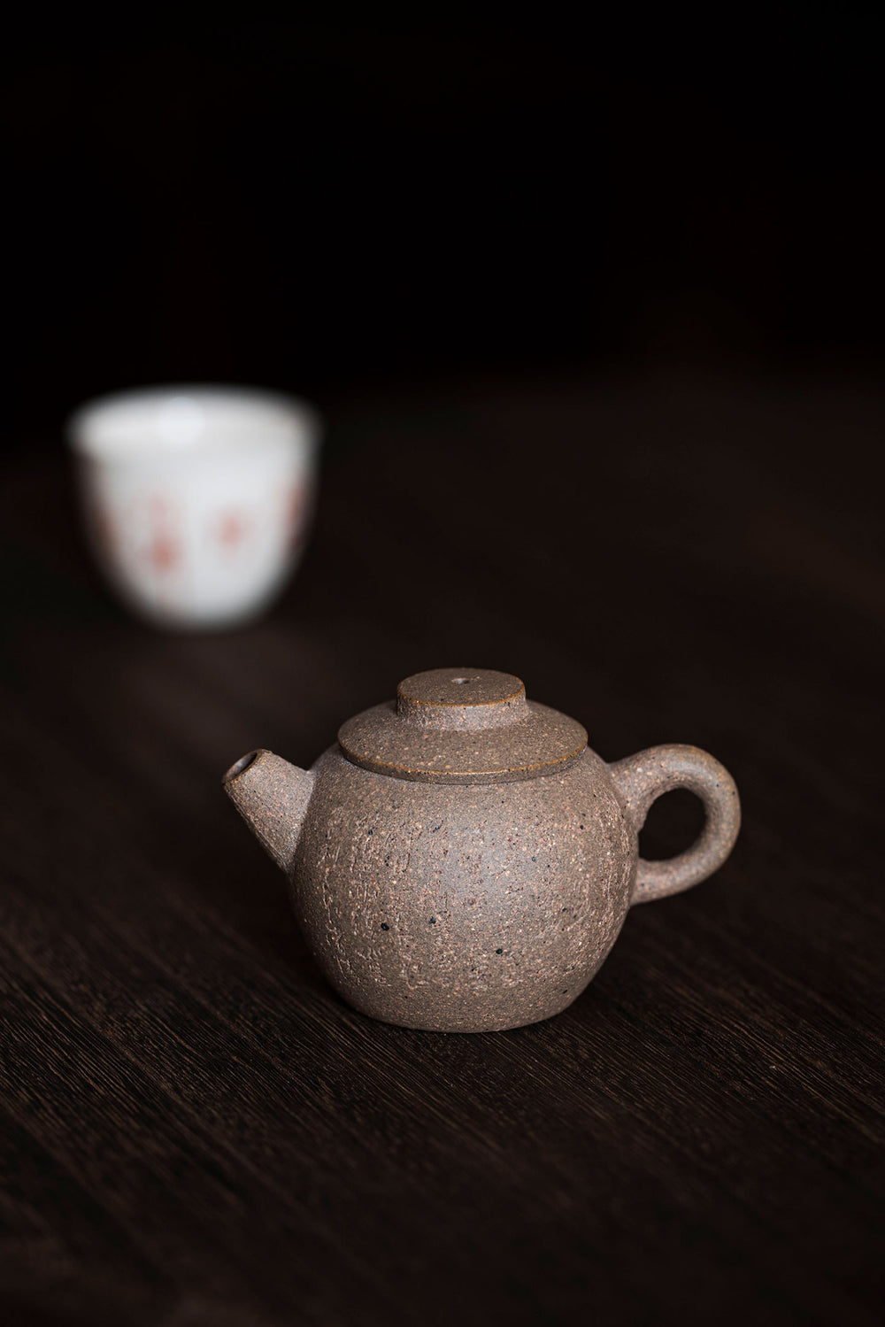 a round mini teapot on a dark wooden surface