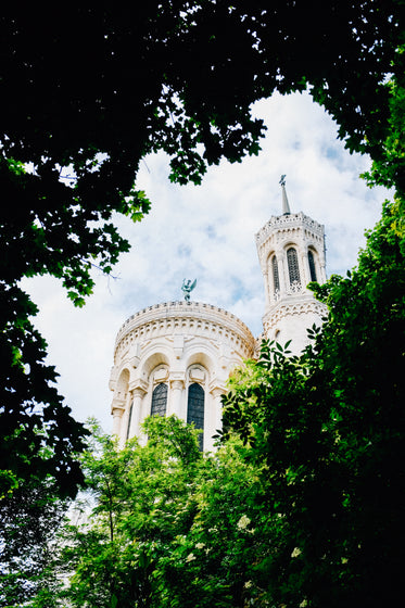 a round white building framed by some green tree branches