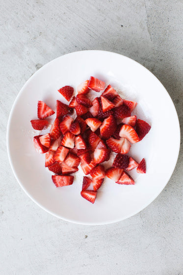 a round white plate full of strawberries