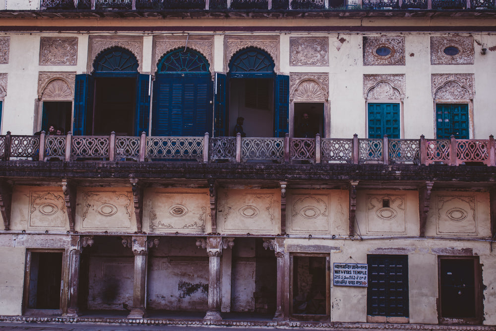 a row of teal doors on a balcony