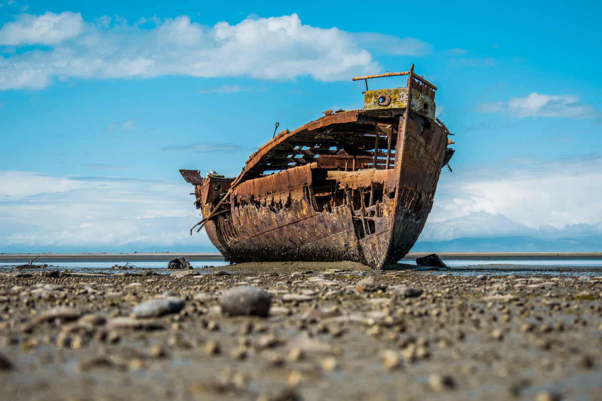 a rusty shipwreck sits on the shore