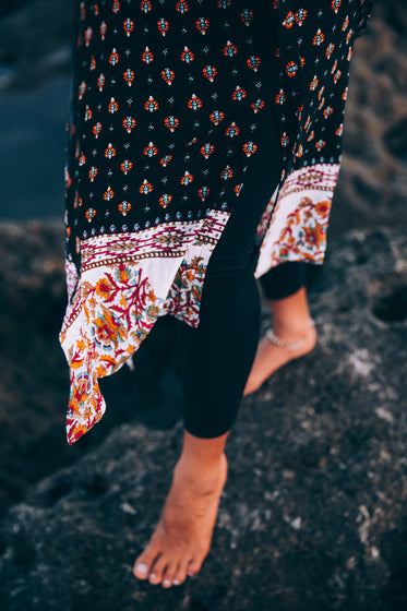 a shawl dangles over a woman's feet in black leggings