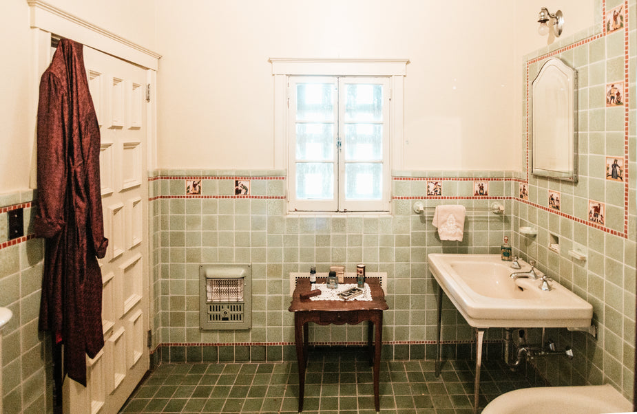 A silk robe hangs on a bathroom door while toiletries have been placed on an ornate table.