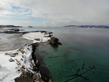 a single house on the water overlooking a frozen landscape