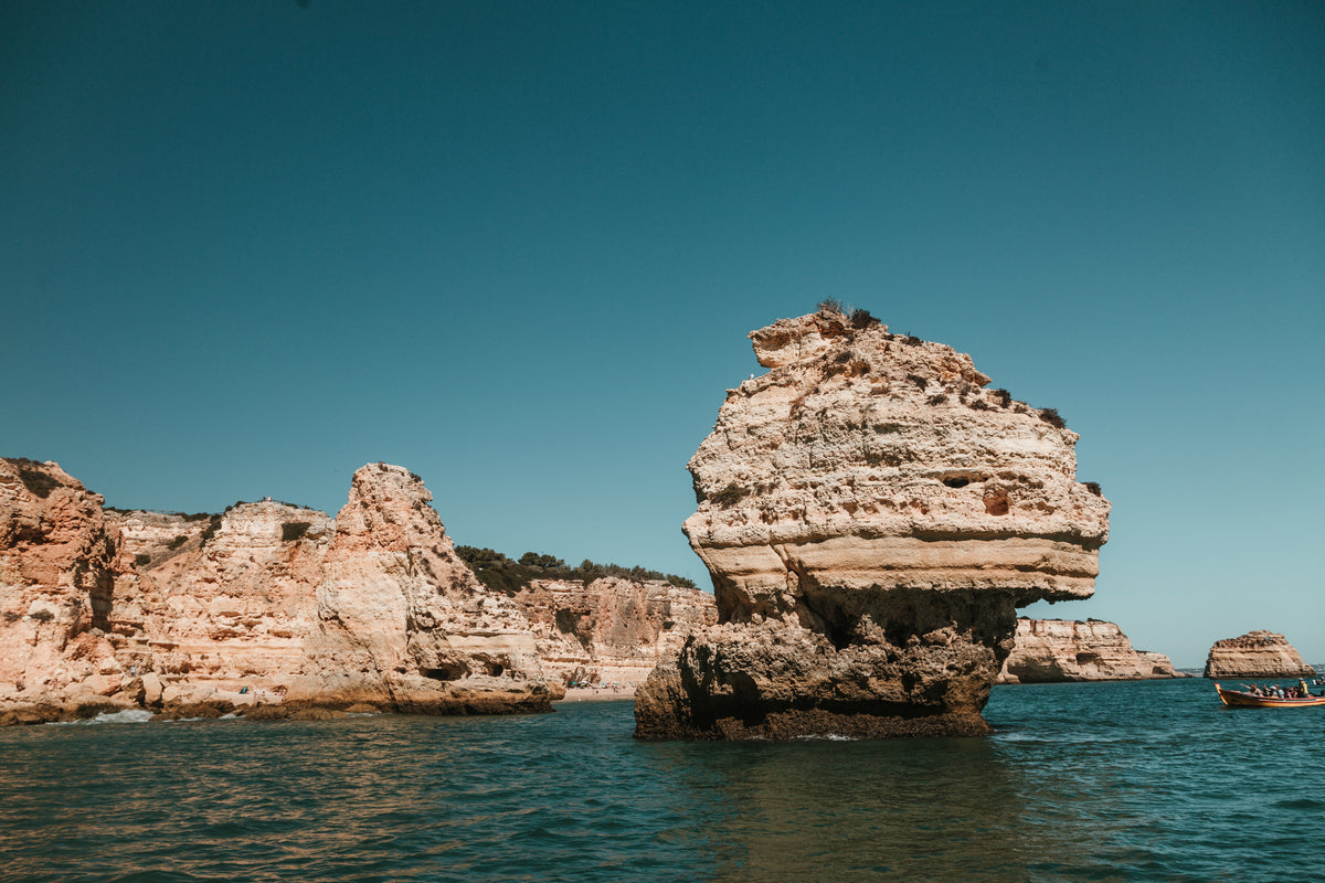 a single rocky stack emerges from blue waters