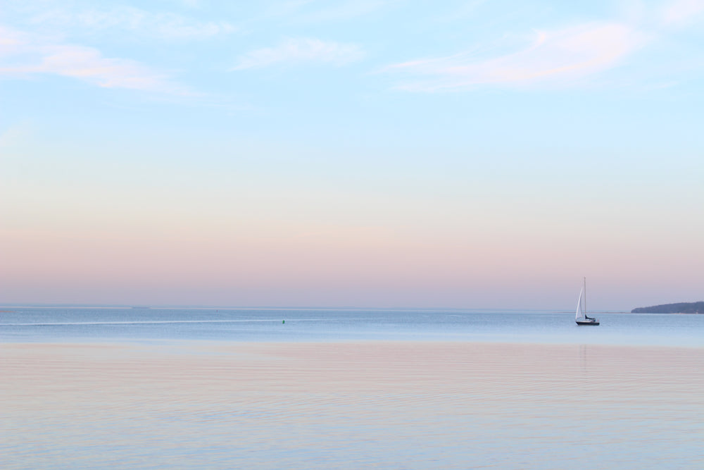 a single sailboat in still waters