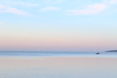 a single sailboat in still waters