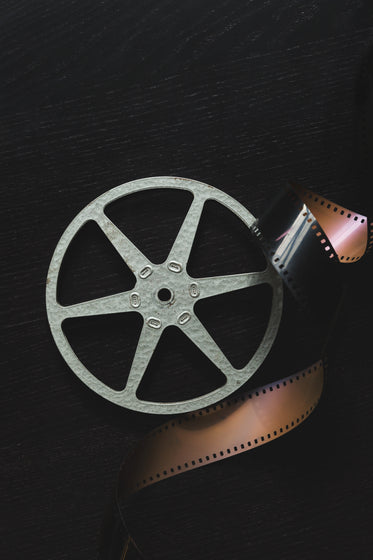 a sliver of film reel curls around a camera sprocket