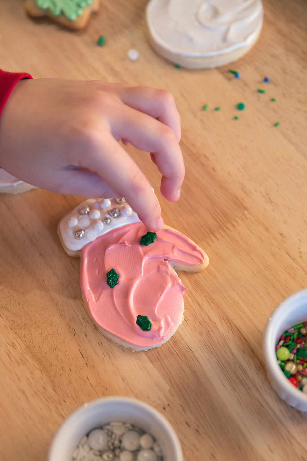 a small hand places sprinkles on a cookie