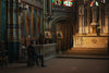 a solitary man in a suit sits on a chair in a baroque church