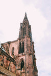a spikey steeple on a gothic red brick cathedral