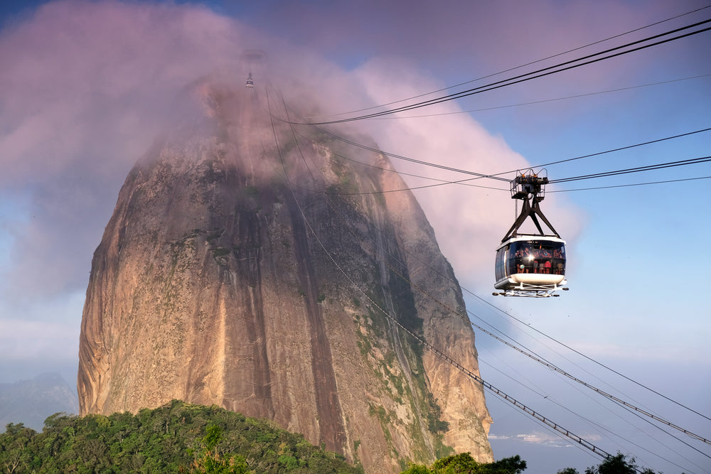 a square gondola and black cables reach up to a mountain