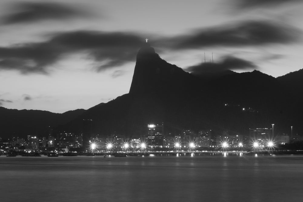 a statue of jesus overlooks the city lights at night