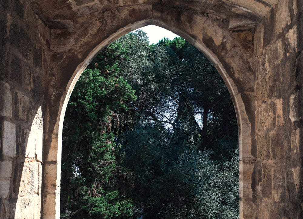 a stone archway looking out to flourishing trees