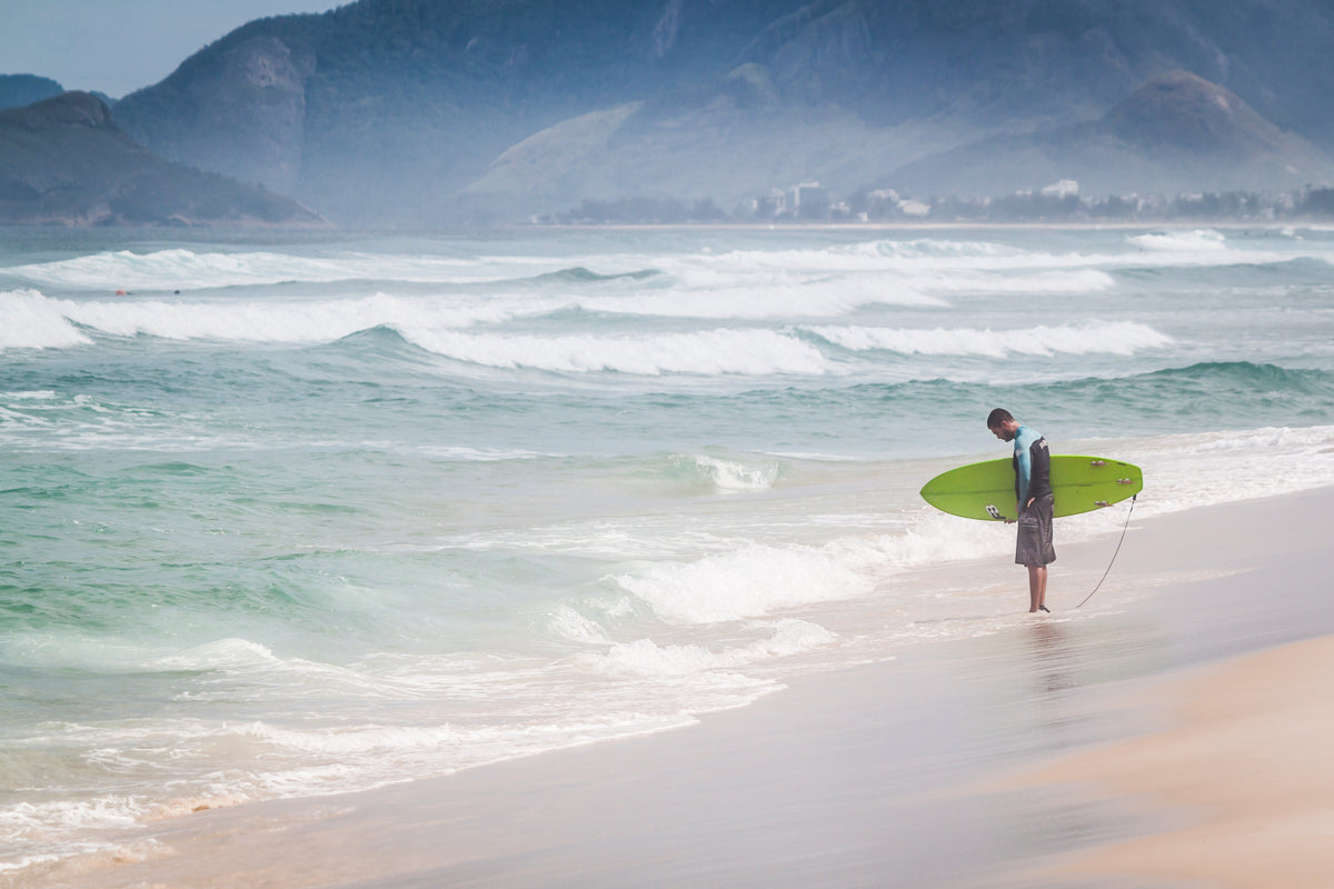 a surfer contemplates the water's edge
