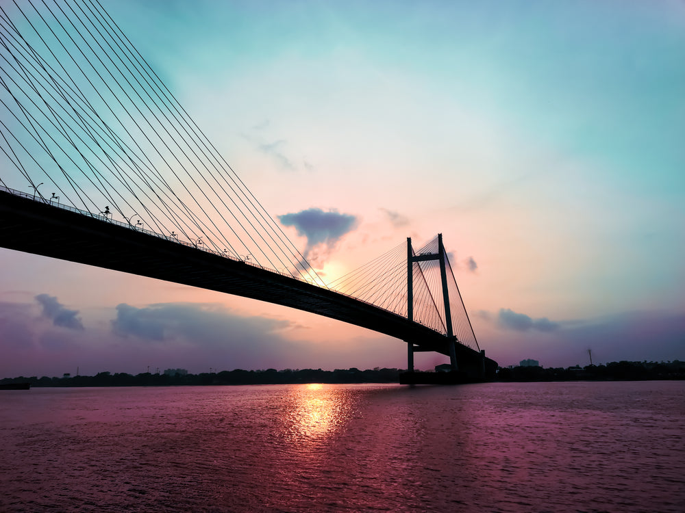 a suspension bridge silhouetted by sunset