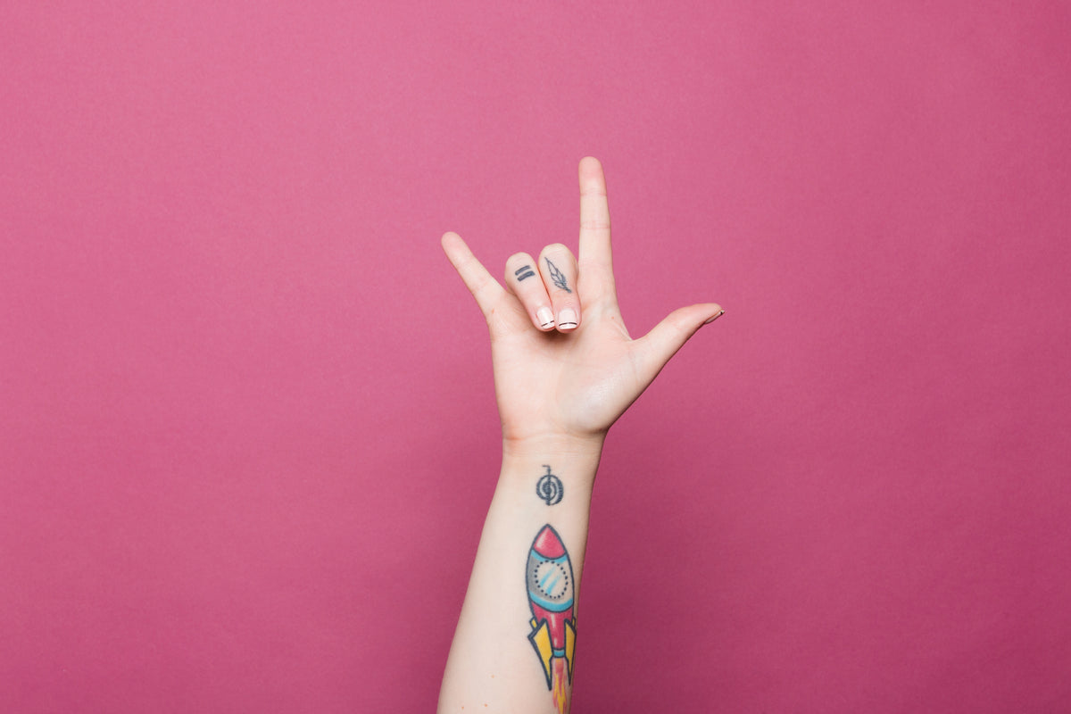 一只纹身的手在做“我爱你”的手势