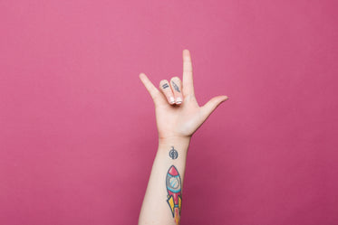 a tattooed hand doing the sign for i love you