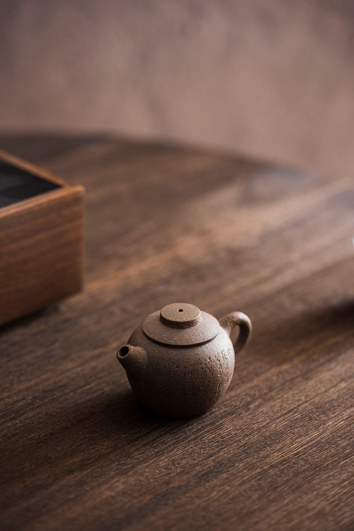 a tiny carved teapot sits on a wooden table