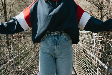 a torso in blue stands holding metal fence